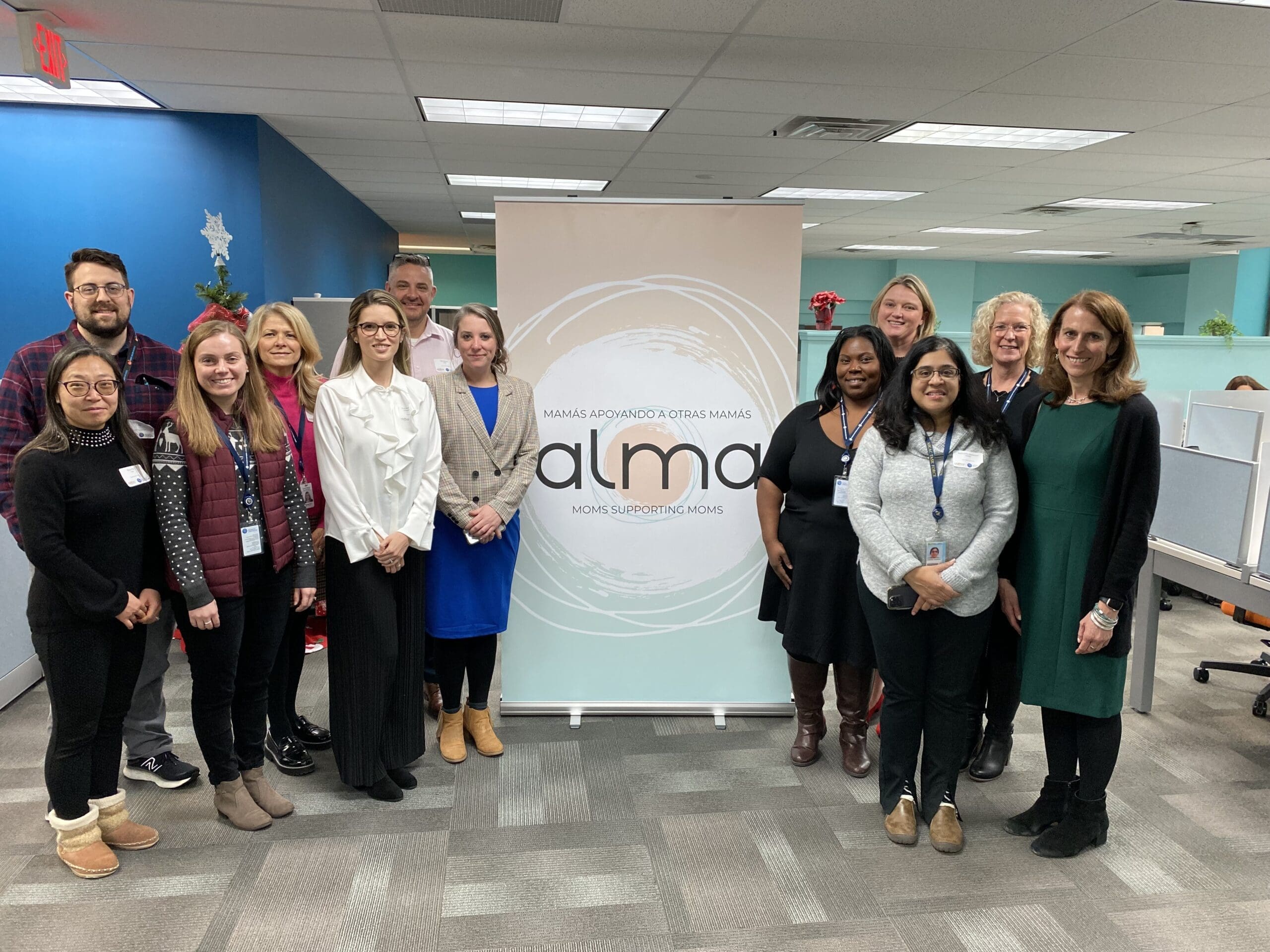 Alma staff members standing together in front of a banner.