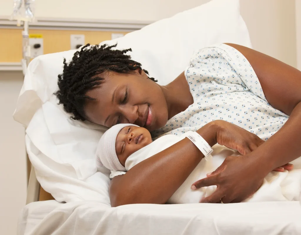 Woman snuggling infant while in hospital bed.