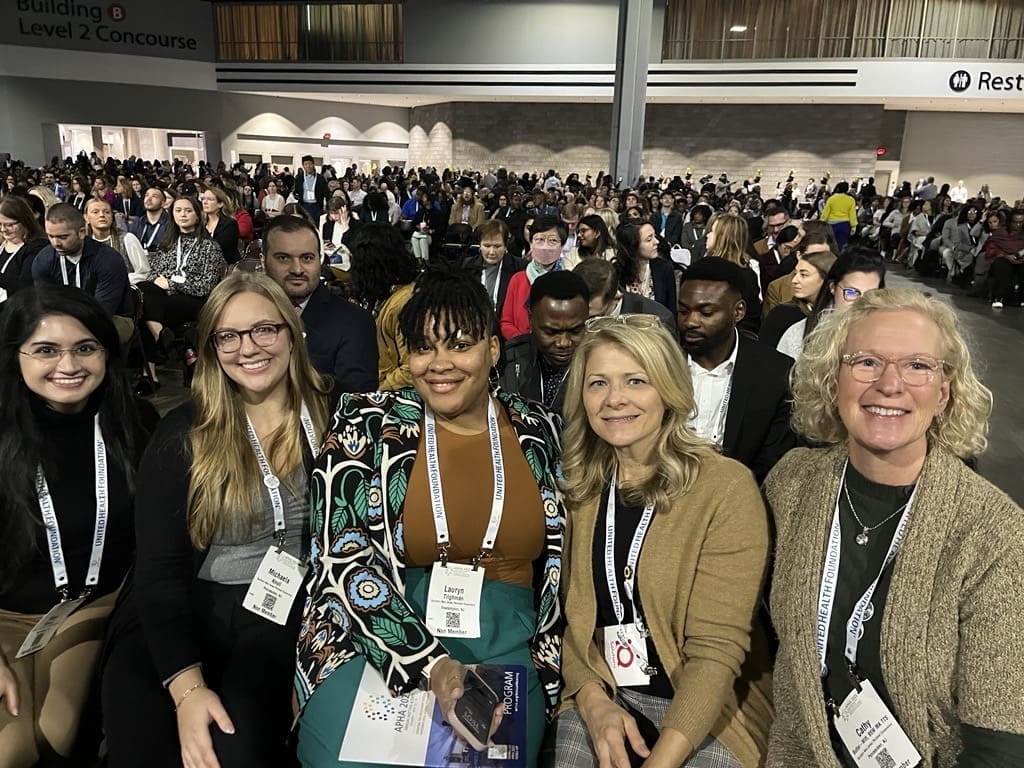 Five staff members from FHI smiling for picture while seated in an auditorium.