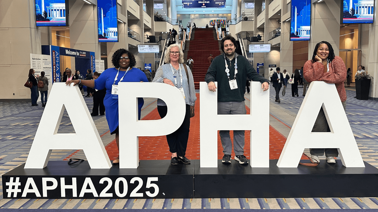 Staff standing behind APHA 2025 sign